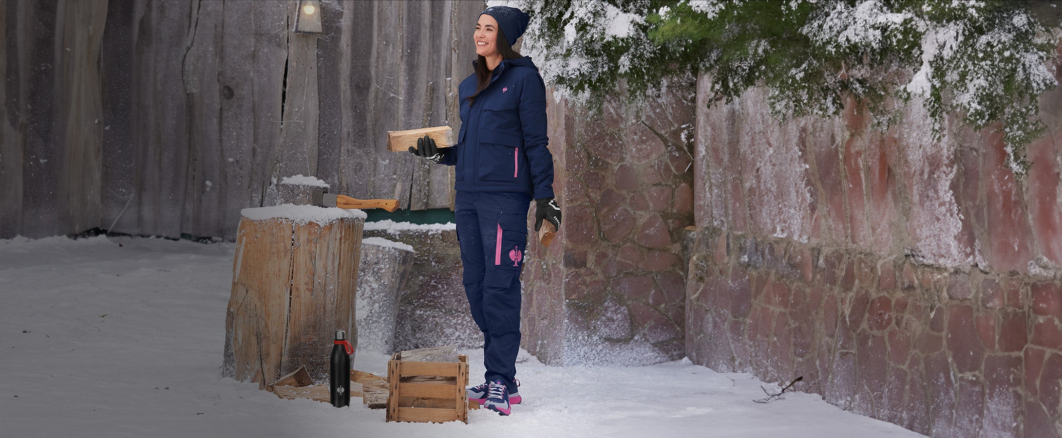 Woman wearing clothing from the e.s.trail collection in a winter setting, with a thermos bottle in front of her