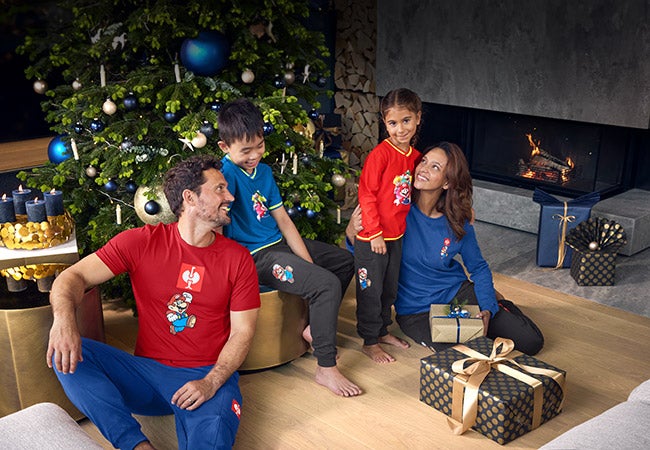 Girl and boy wearing clothing from the Super Mario x Strauss collection in a Christmas living room
